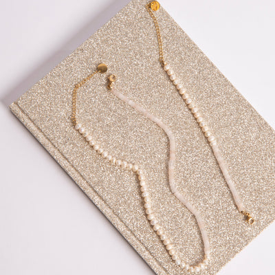 Sui Ava Armbånd Vanilla med hvite perler og justerbar lås i messing, vist sammen med Sui Ava Halskjede Vanilla i samme serie